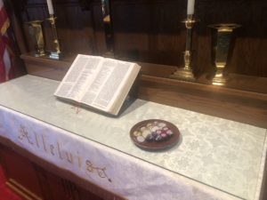 Communion elements individually wrapped and packaged on altar near Bible.