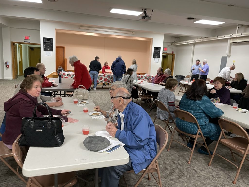 Folks at tables in fellowship hall socializing