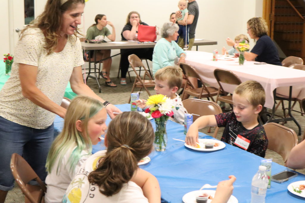 children eating a snack around a table at VBS