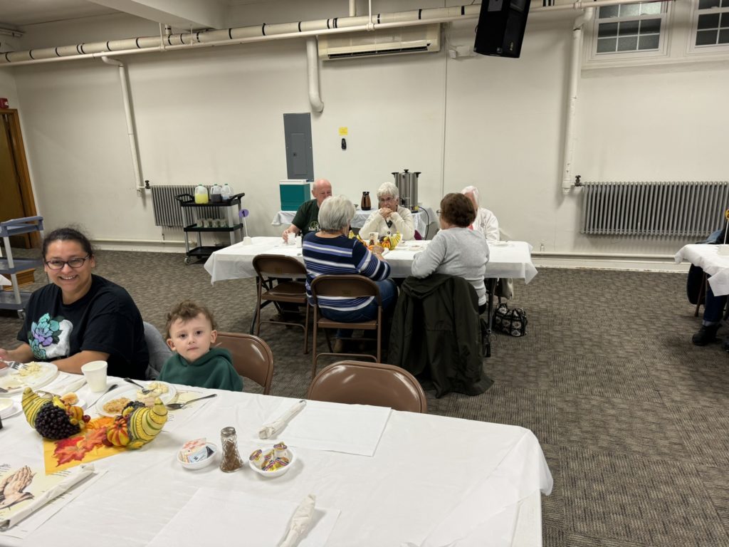 People sitting around tables eating our November community dinner.