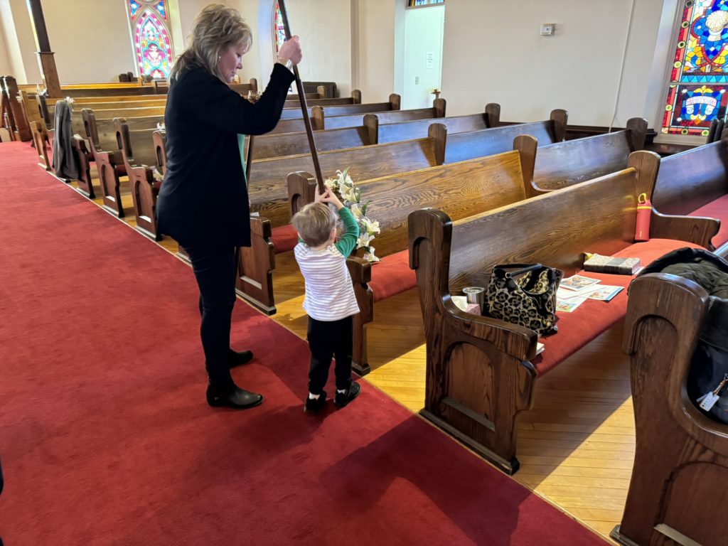 decorating for Easter day-child helps put candle post on pew with an adult